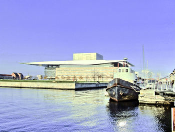 Boat in river in front of city against blue sky