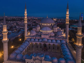 Illuminated buildings in city against sky at dusk