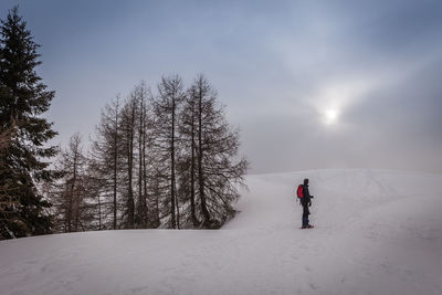 Person skiing on snow covered field against sky