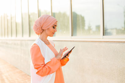 Woman holding umbrella while standing on mobile phone