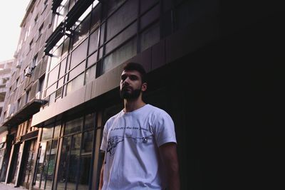 Portrait of young man standing against building