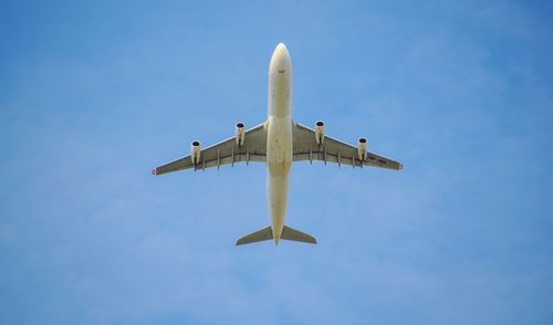 Low angle view of airplane flying against blue sky