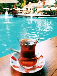 Close-up of drink on table by swimming pool