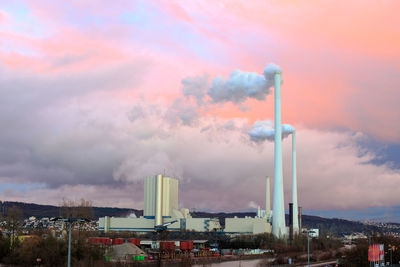 Smoke emitting from factory against sky