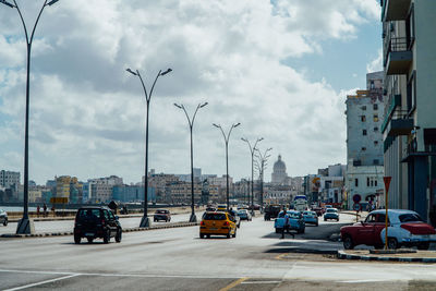 Cars on street in city against sky