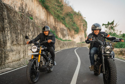 Side view of man riding motor scooter on road