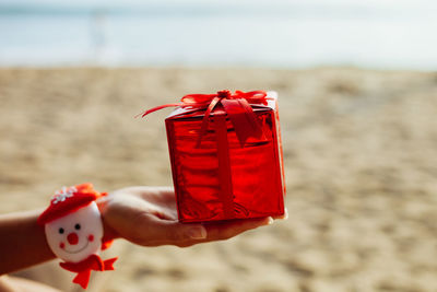 Close-up of hand holding red gift box at beach