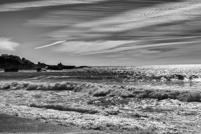 Waves rushing on shore against sky