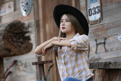 Young woman looking away while standing against wall