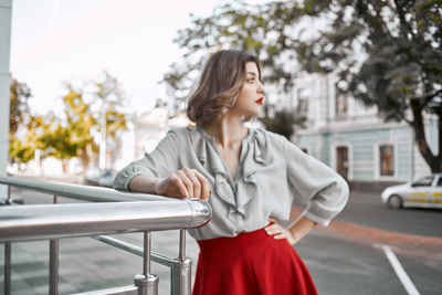 Mid adult woman looking away while standing on street in city