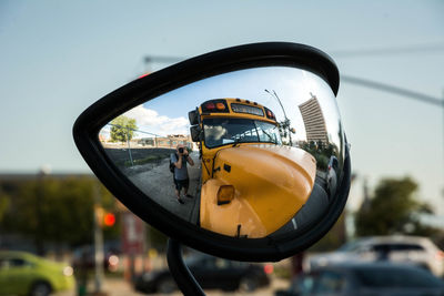 Photographer taking self portrait in side-view mirror of school bus