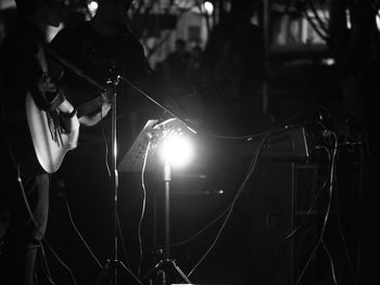 Midsection of musician playing guitar at night