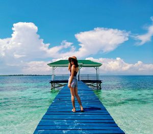 Woman standing on jetty over sea against sky