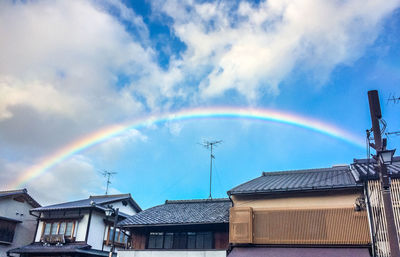 Low angle view of rainbow over buildings against sky
