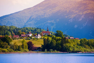 Scenic view of lake by buildings against mountain