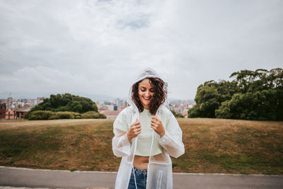 Smiling woman standing in park against sky