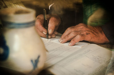 Midsection of man writing in book