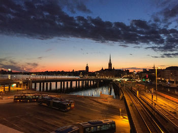 Illuminated bridge over river against sky at sunset