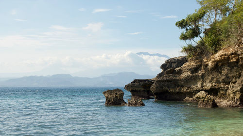 Rock formation in sea against sky