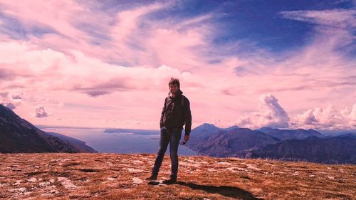 Full length portrait of man standing on mountain against sky