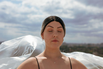 Portrait of beautiful young woman against sky