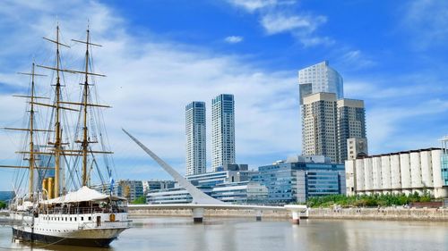 Boats moored in river by city against sky