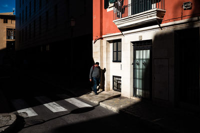 Full length of man walking on street amidst buildings