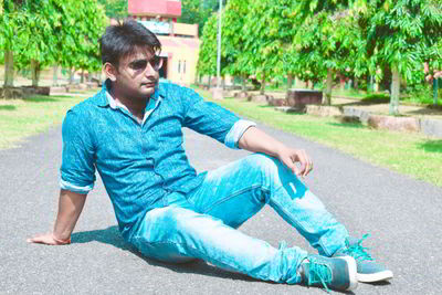 Young man looking away while sitting outdoors