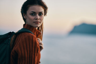 Portrait of young woman against sea during sunset