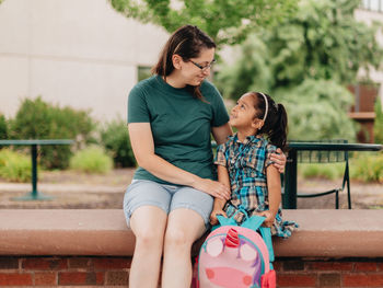 Young millennial mother sending daughter off back to school