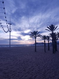 Silhouette trees on beach against sky at sunset