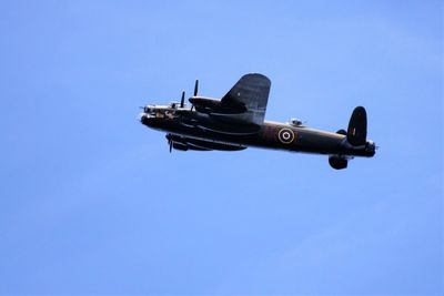 Low angle view of airplane flying against clear blue sky