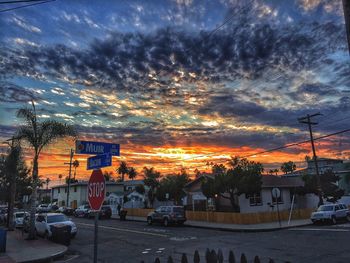 Vehicles parked on road against buildings at sunset