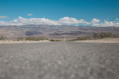 Road by desert against sky