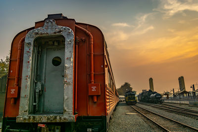 Train on railroad tracks against sky during sunset