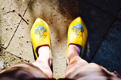 Low section of person wearing yellow wooden shoes