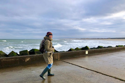 Rear view of woman standing at beach against sky