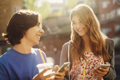 Smiling young woman using smart phone outdoors