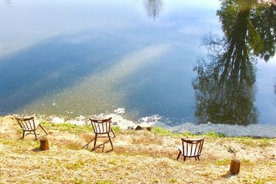 Chairs and table by lake against sky