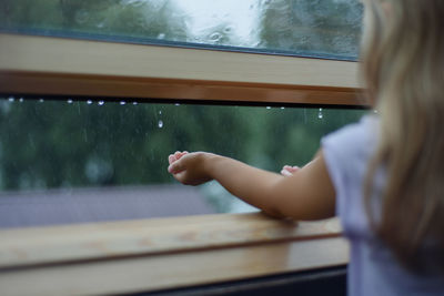 Midsection of woman looking through window