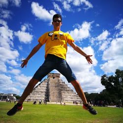Low angle view of man jumping on field at el castillo chichen itza