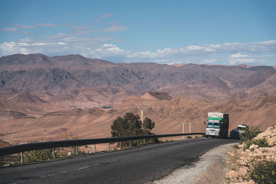 Road by mountains against sky