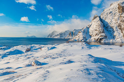 Scenic view of snowcapped mountains by sea against sky