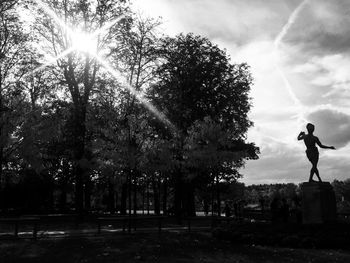 Trees by statue against sky