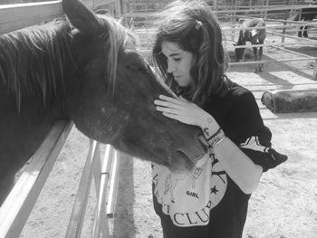 Young woman with horse standing at ranch