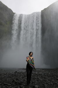 Full length of woman standing against waterfall