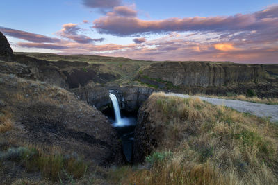 Scenic view of waterfall against sky during sunset