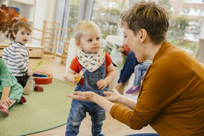 Pre-school teacher playing with little boy in kindergarten