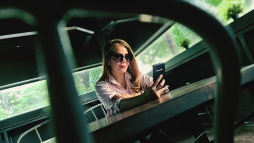 Young woman using mobile phone while sitting at cafe