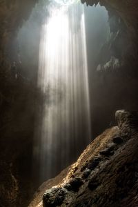 Low angle view of sunlight streaming through rocks in forest